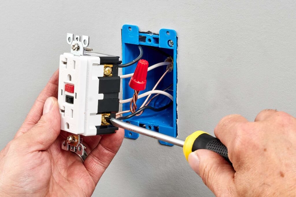 Licensed electrician repairing a wall outlet and wiring a receptacle inside an electrical box